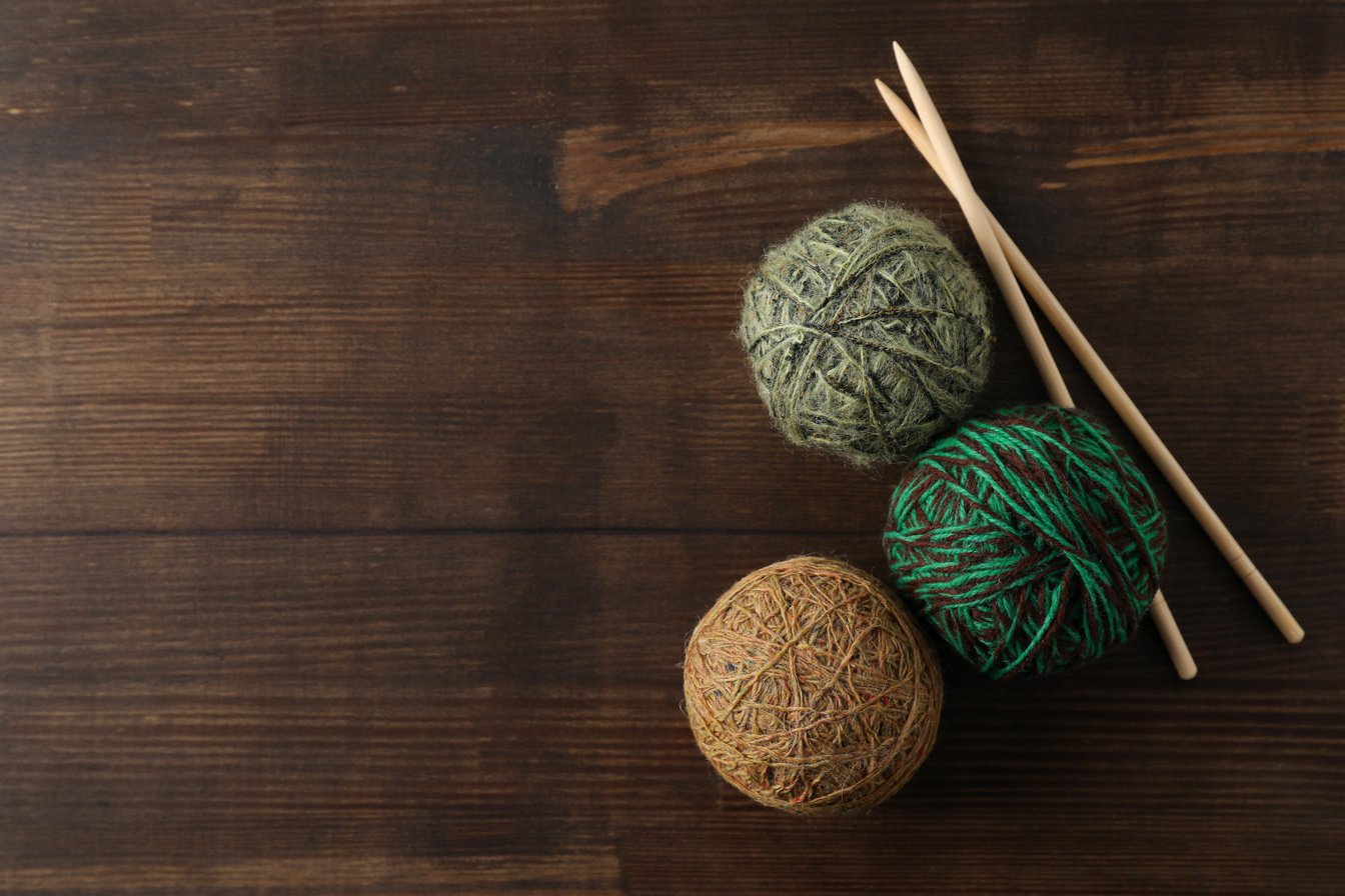 Yarn Balls and Knitting Needles on Wooden Background